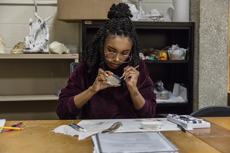 woman of color using art supplies at a table