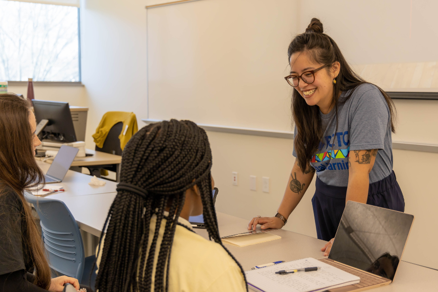 Student standing infront of a sitting student talking. 