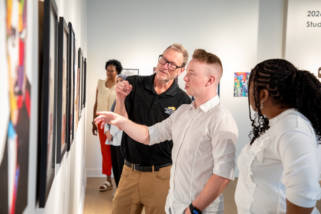 two men looking at art in the gallery with others nearby