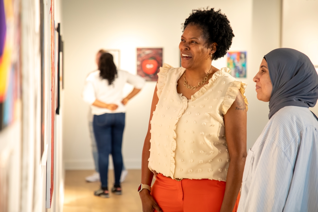 two women looking at art in the gallery with others in the background