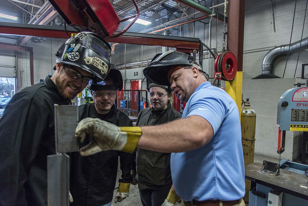 Three welding students being instructed in welding class