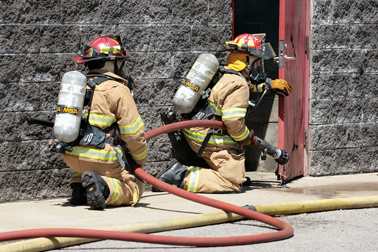 Fire fighting students practicing entering a building. 