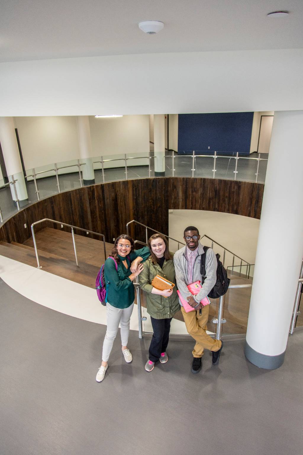 Three students standing next to staircase