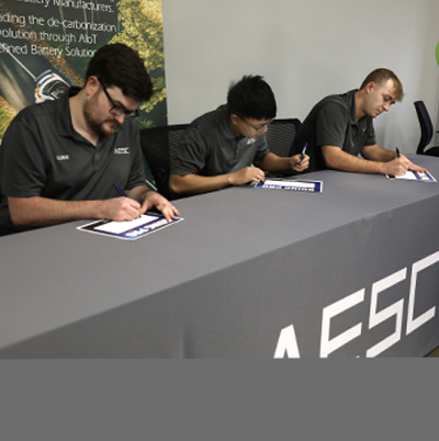 Three male SKYCTC student signing going pro commitment cards with AESC.