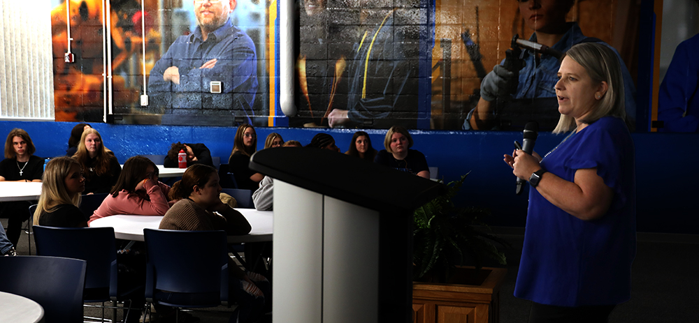 Angie Harlan standing at a podium talking to students