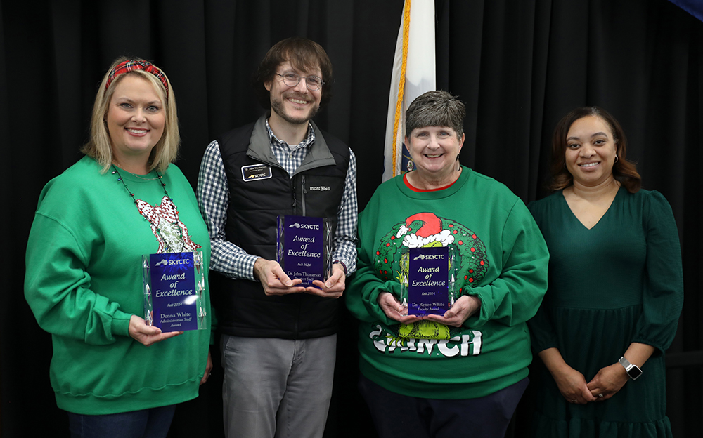 Three people receiving awards with a presenter