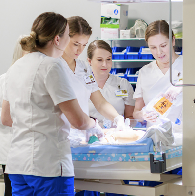 Four female nursing student in nursing lab working with maternity simulation