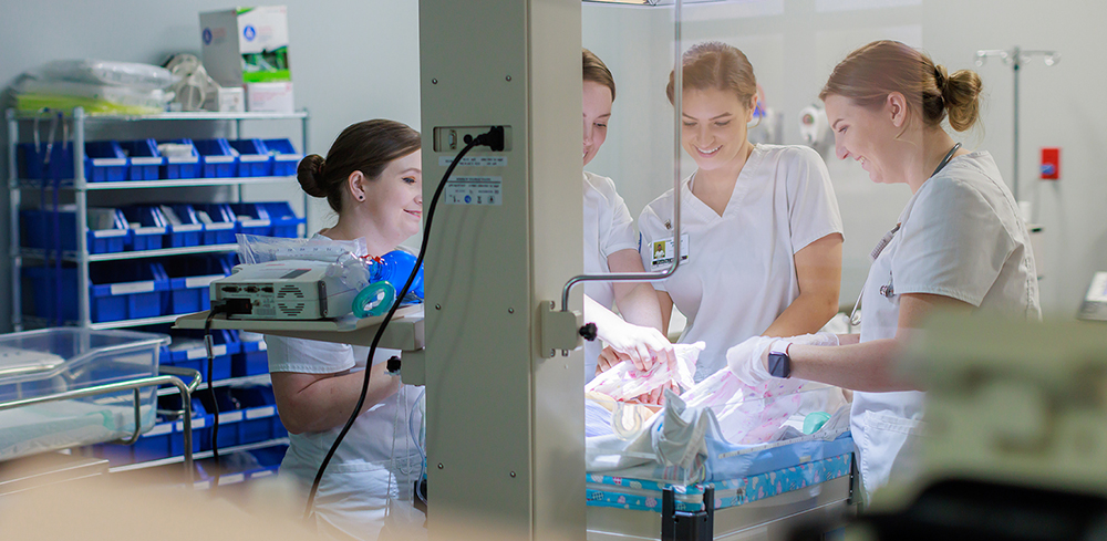 Four femal nursing student working in nursing lab with maternity simulation