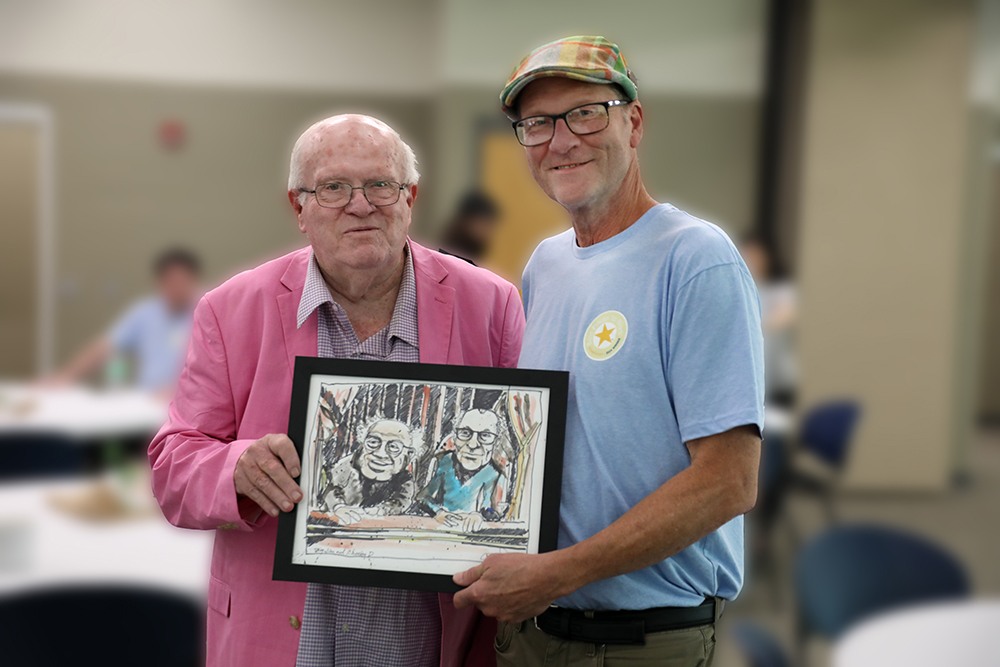 "SKYCTC Associate Professor of Art, David Jones (right), presents an original sketch to Jim Turner at his retirement celebration. Turner's five-decade career in teaching and journalism is honored with the sketch humorously portraying him and Jones as the iconic Muppet characters Statler and Waldorf, renowned for their witty banter and heckling on 'The Muppet Show'."