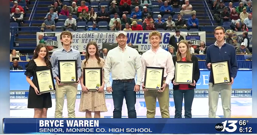 Seven high school students standding at mid-court holding their scholarship awards