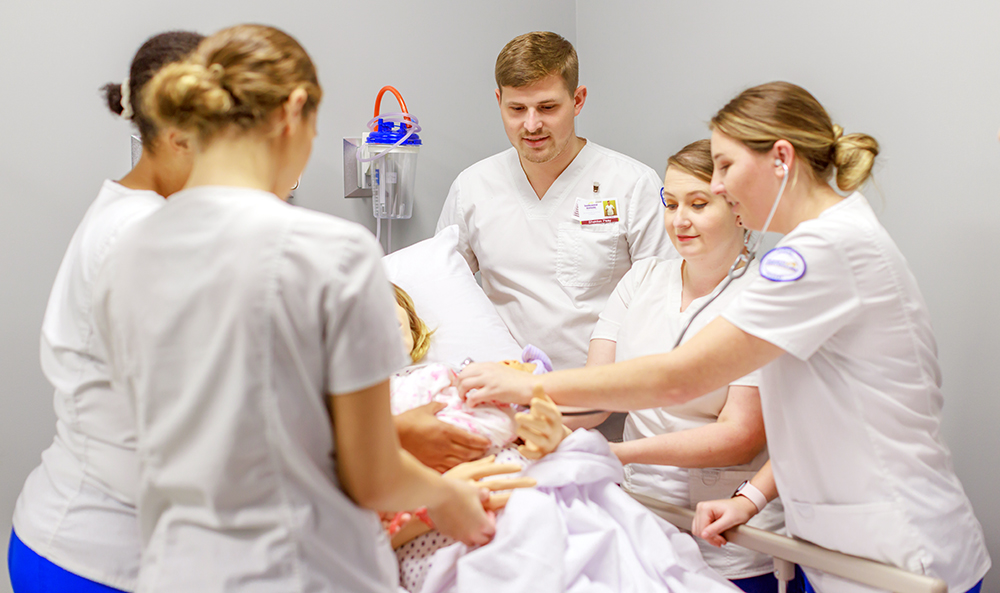 Nursing students working with a patient at bedside