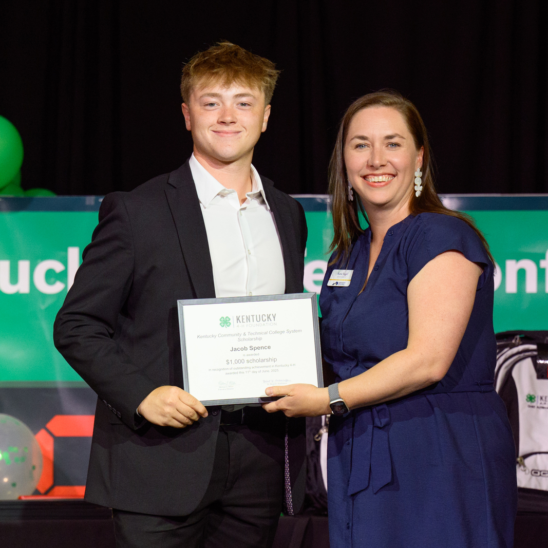 Student receiving award on stage from female sponsor