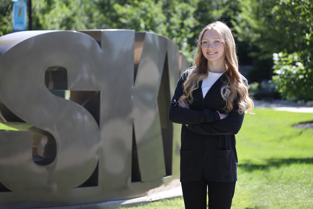 Aliza Wilson standing next to the SKYCTC sculpture on the campus of Southcentral Kentucky Community and Technical College