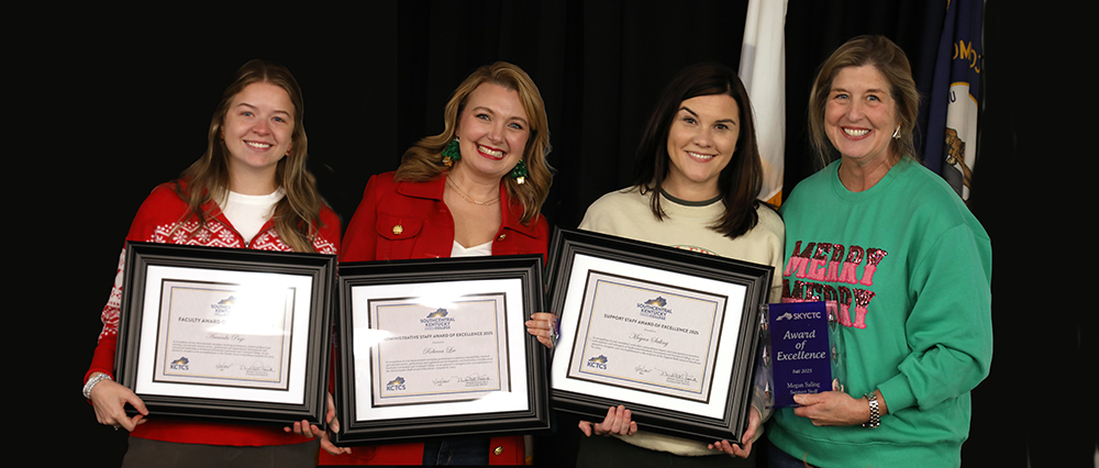 Four ladies holding up plaques and trophy