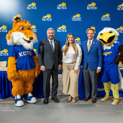 Two college mascots and three other people standing in front of a KCTCS logoed background