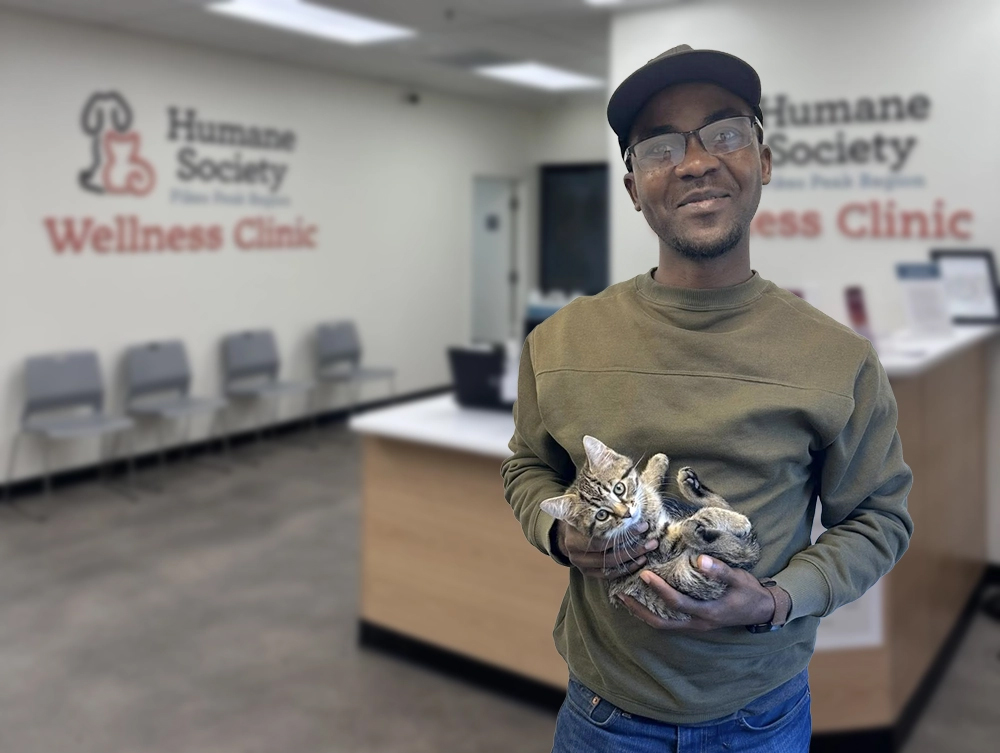 Kibe Wilondja holding a cat at the humane society