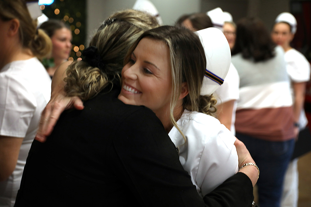 Nursing graduate in uniform being hugged at pinning ceremony