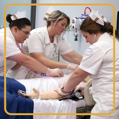 Three female nursing students working on a patient in simulation lab.