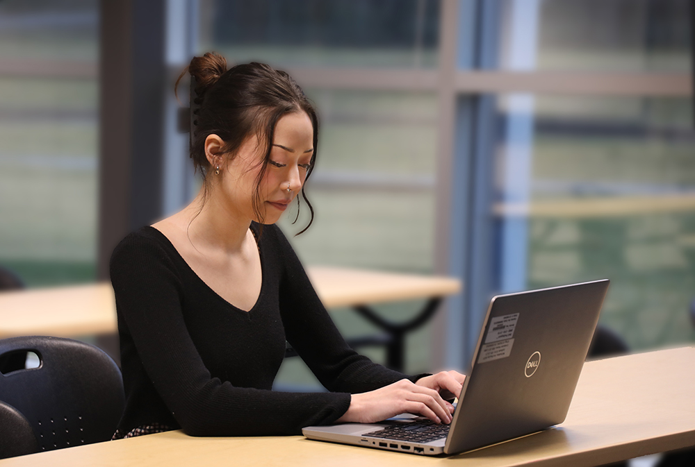 Paris Carlson in a classroom working on a laptop