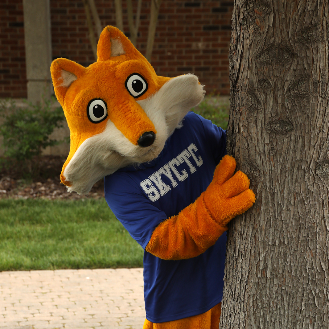 Pathfinder mascot in costume peeking out from behind a tree