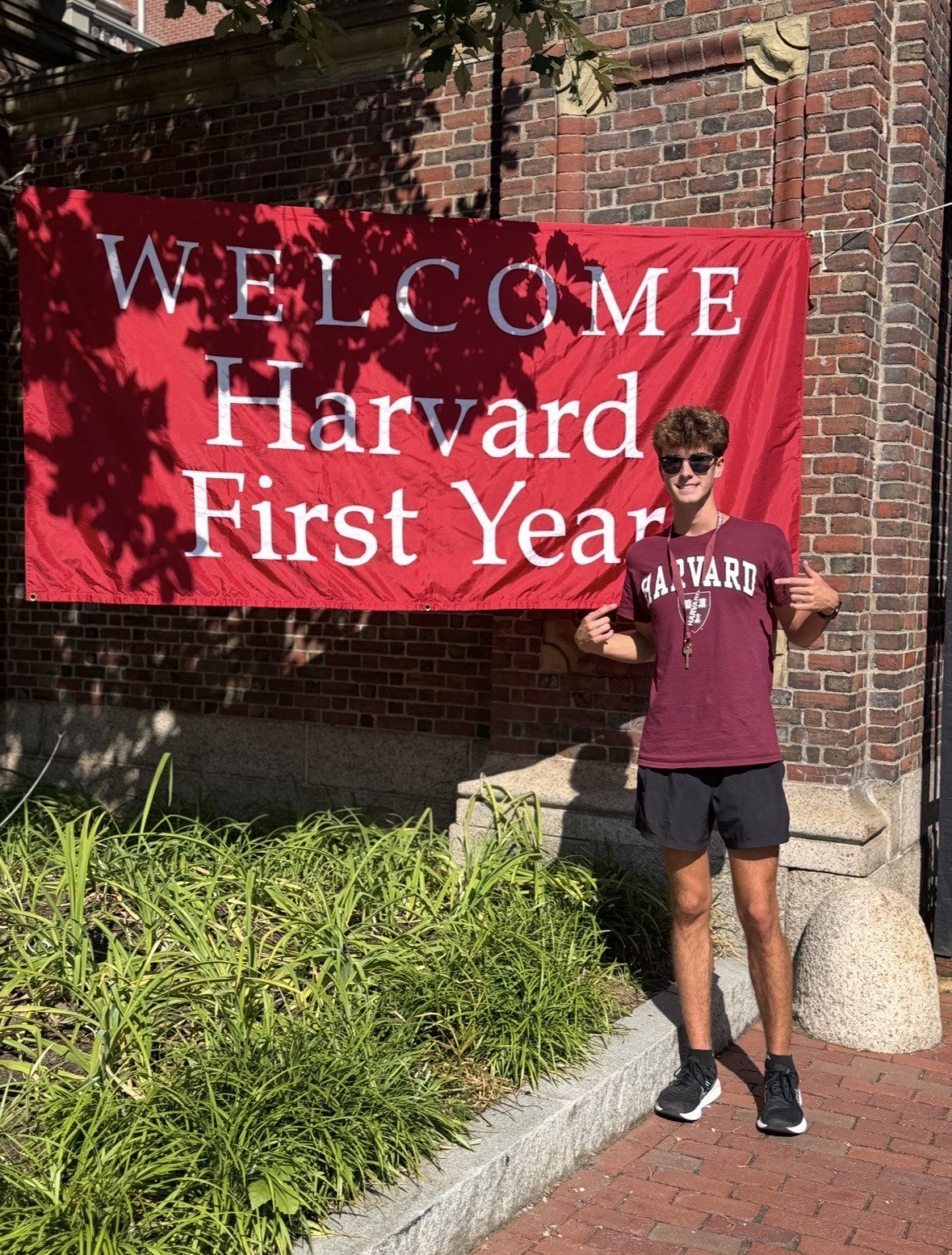 Braden Johnson standing on Harvard Campus next to sign that says welcome to Harvard first year students.