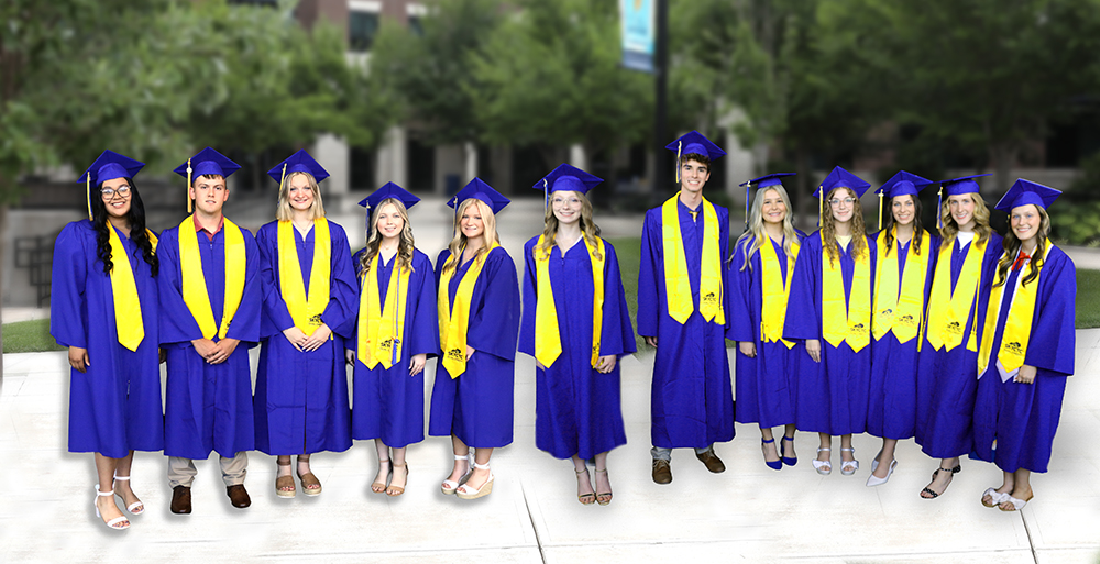 Dual credit graduates standing in front of  campus in cap and gown.
