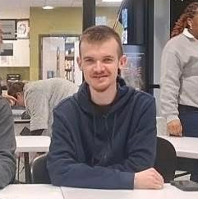 Photo of Brenton Lundgrin at his desk at college