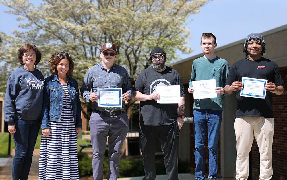 Two female FBLA Collegiate advisors and four male student state winners stand holding their awards certificates