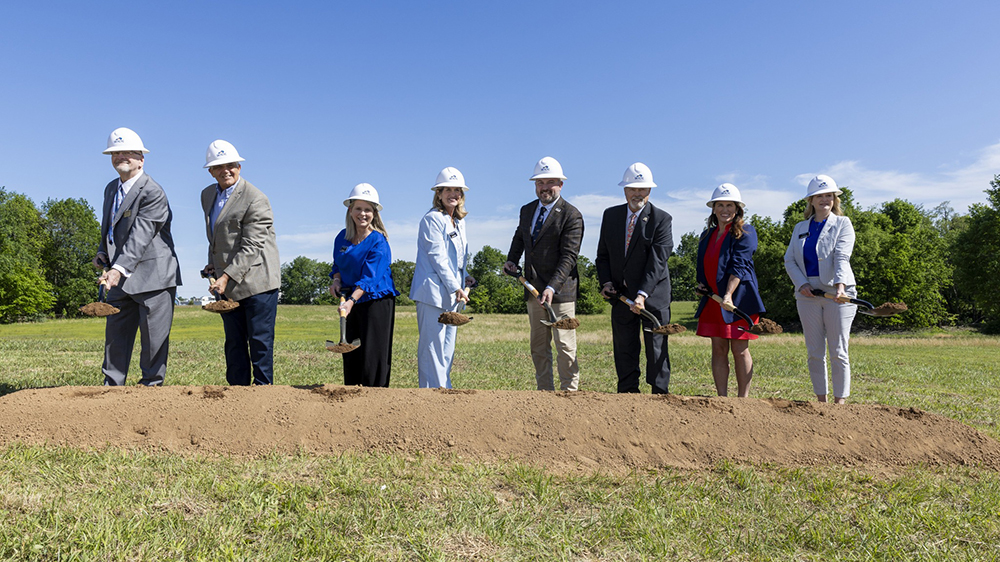 Eight people with shovels throwing dirt at groundbreaking