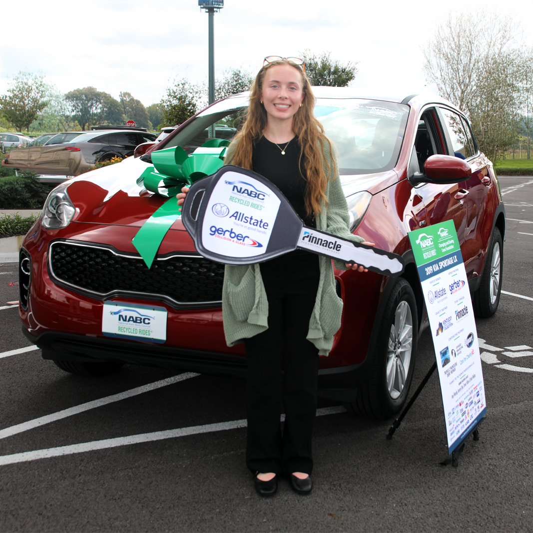 Lady standing in front of donated car holding an oversized key