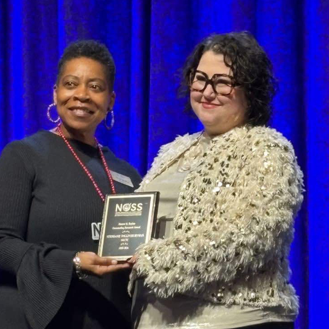 Two ladies holding a plaque