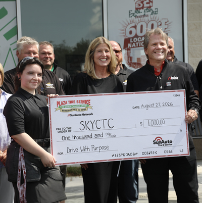 Two ladies and one man holding an oversized scholarship donation check