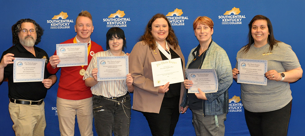 Six people standing in front of background holding award certificates
