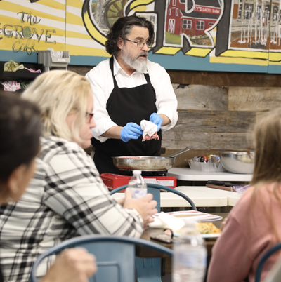 Male instructor demonstrating cooking techniques in front of group of students