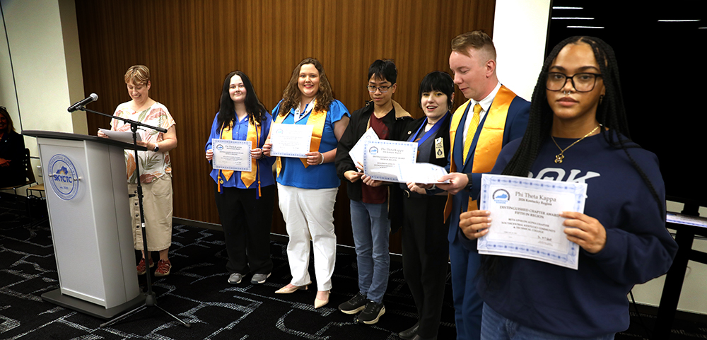 Student standing holding certificates