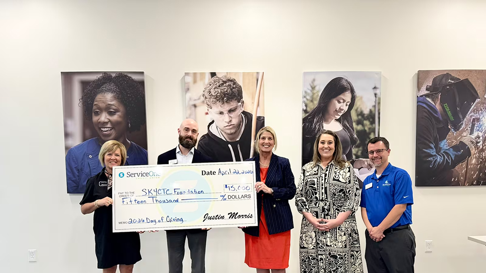 Three members of service one credit union present a check to representitives of SKYCTC