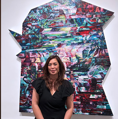 Sisavanh Phouthavong standing in front of one of her paintings