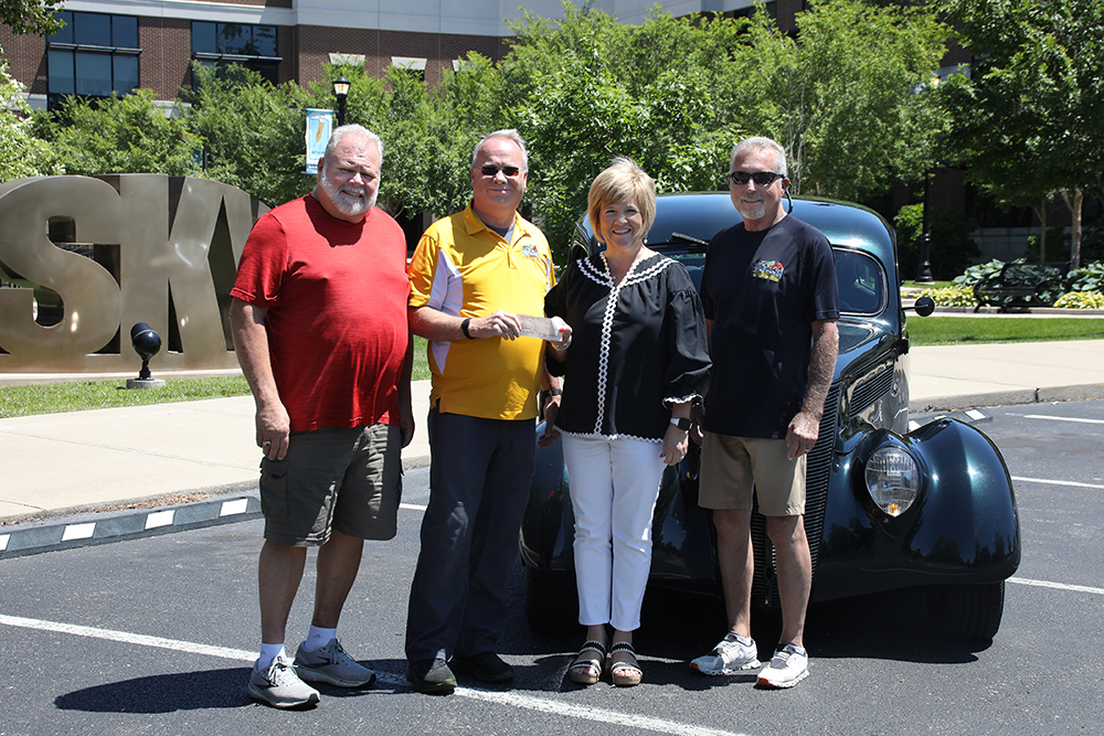 Three men presenting a scholarship check to Heather Rogers of SKYCTC