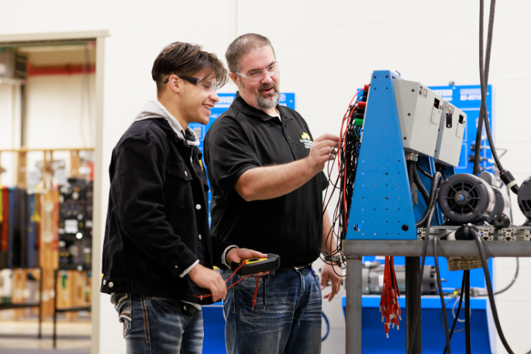 Instructor teaching student how to work on a machine