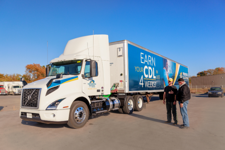 2 individuals standing beside a semi-truck
