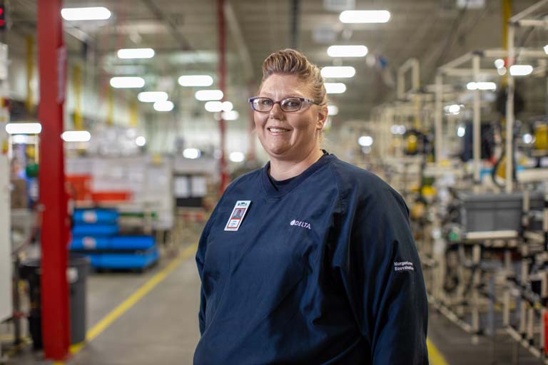 Jamie Lindsey stading in middle of a factory setting