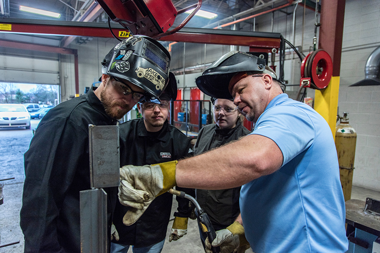 Welding instructor showing students the difference between a good weld and a bad weld